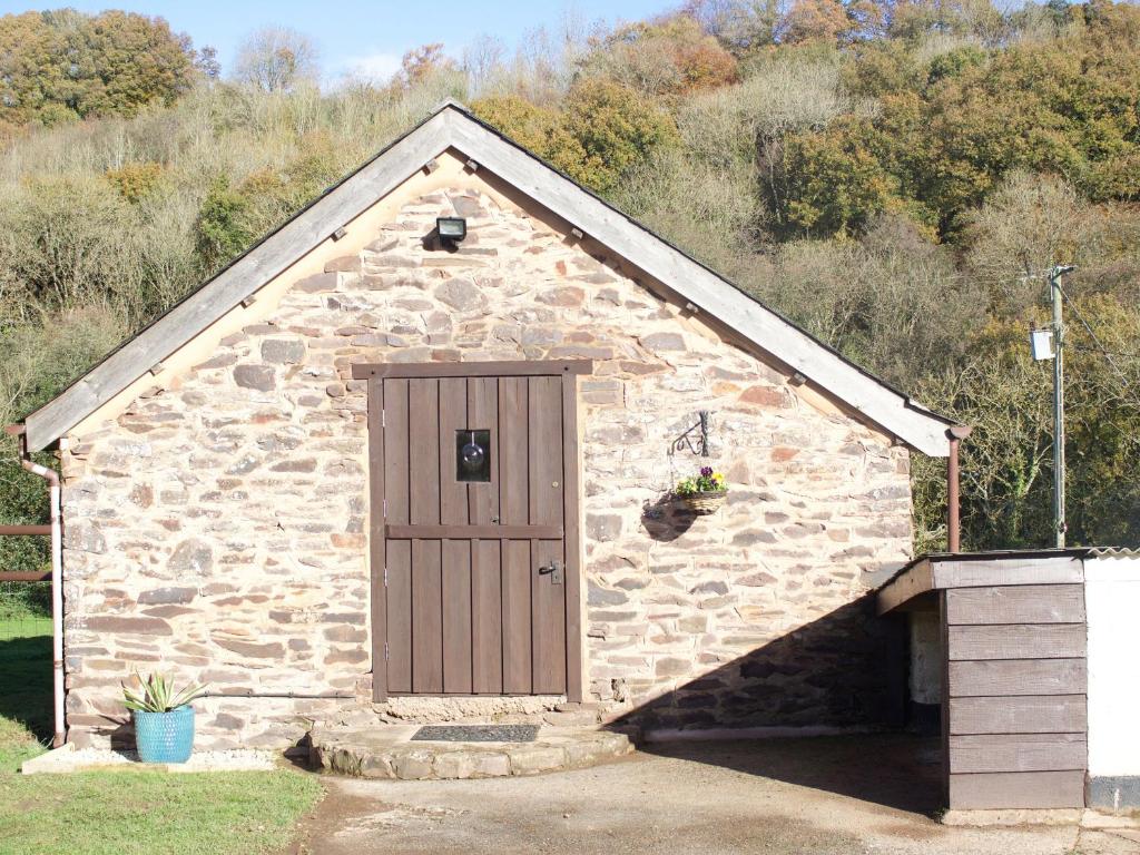 a small stone building with a wooden door at Crooke Barn in Tiverton