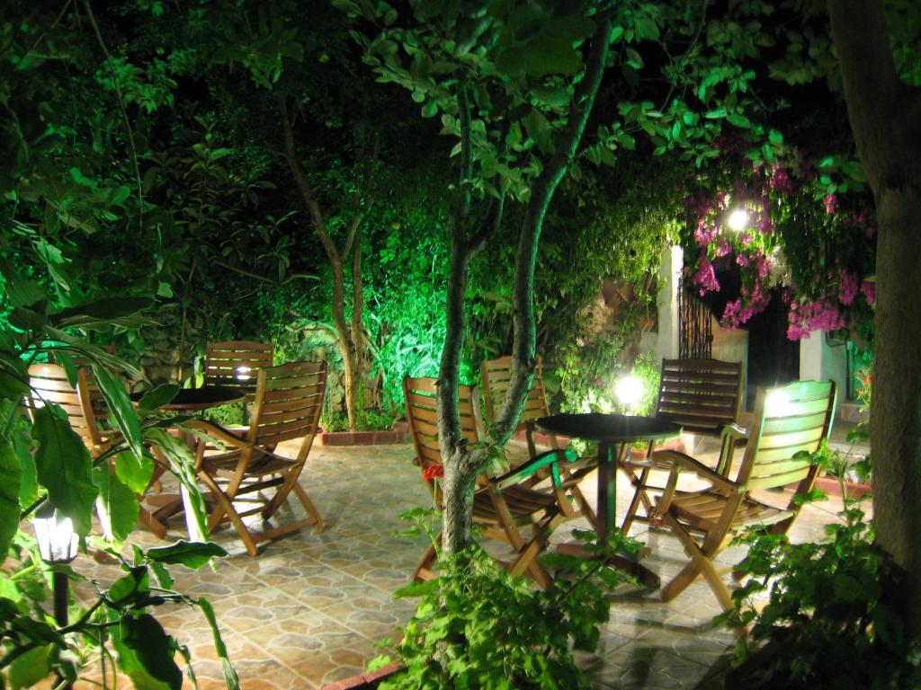 un patio con sillas, mesas y árboles por la noche en Eleftheria Lindian Studios I, en Lindos