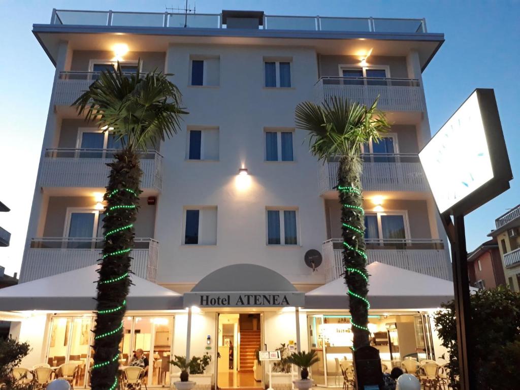 a hotel with palm trees in front of a building at Hotel Atenea Golden Star in Caorle
