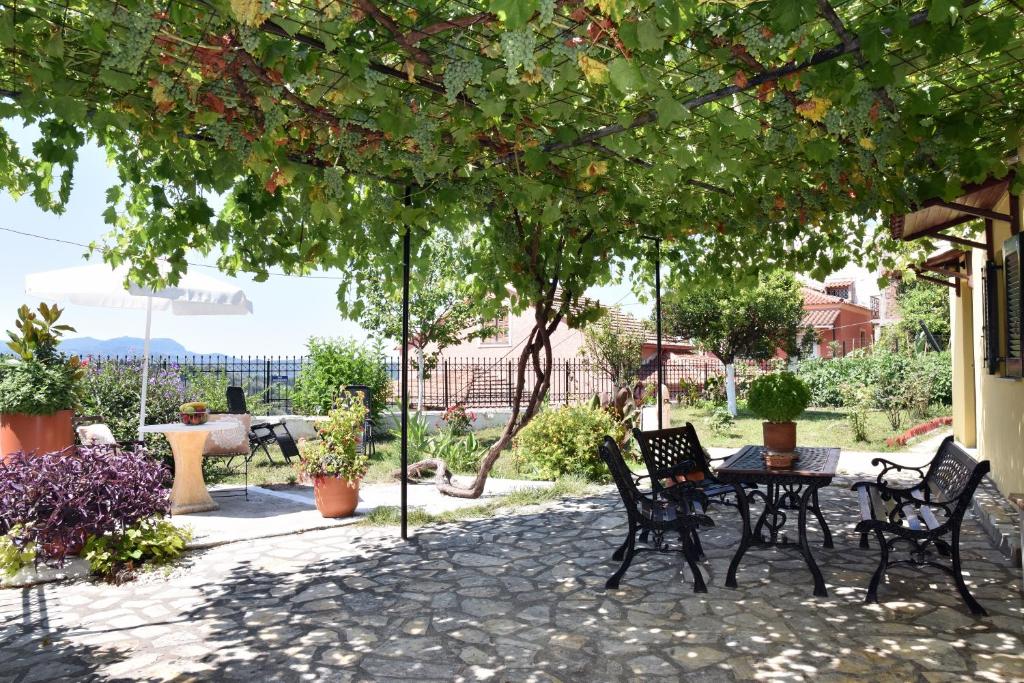 a patio with a table and chairs under a tree at Traditional Cottage on the hillside of Antiperni in Antipernoí