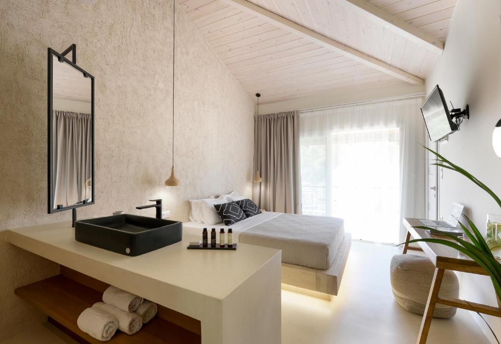 a bedroom with a bed and a bathroom with a sink at Karidi Beach Boutique Suites in Vourvourou