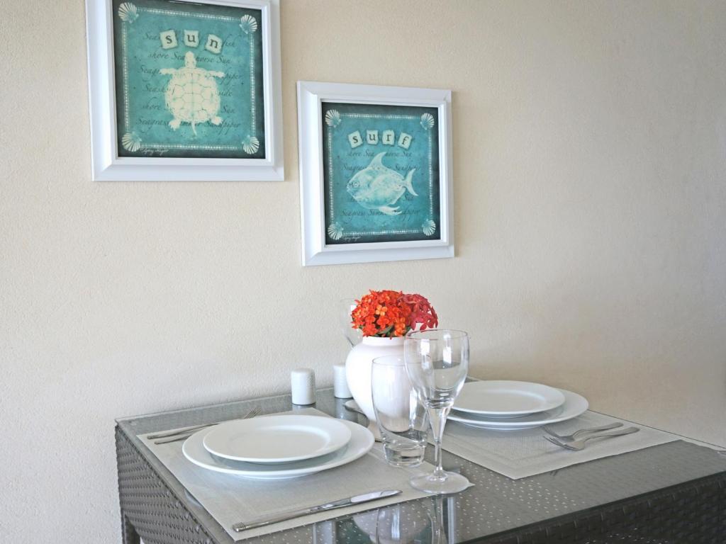 a dining table with two plates and a vase with flowers at Lantana Resort Barbados by Island Villas in Saint James
