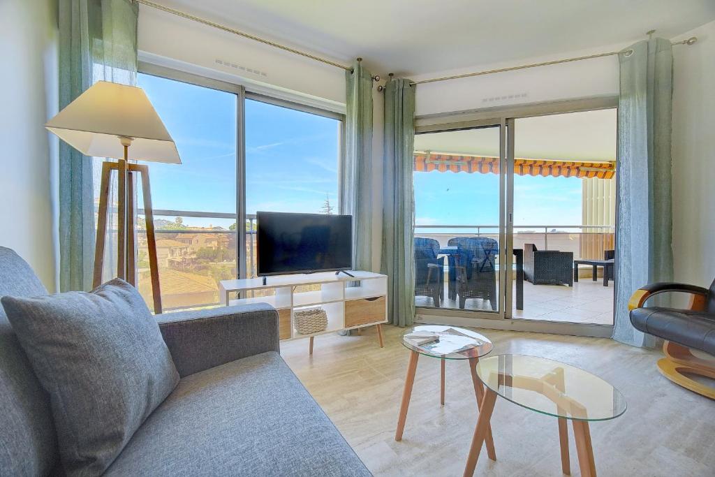 Il comprend un salon avec un canapé, une télévision et un balcon. dans l'établissement IMMOGROOM -Panoramic sea view terrace-2min from the beach, à Cannes