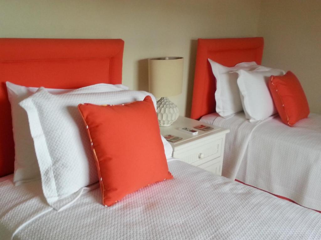 two beds with red and white pillows in a bedroom at Lantana Resort Barbados by Island Villas in Saint James