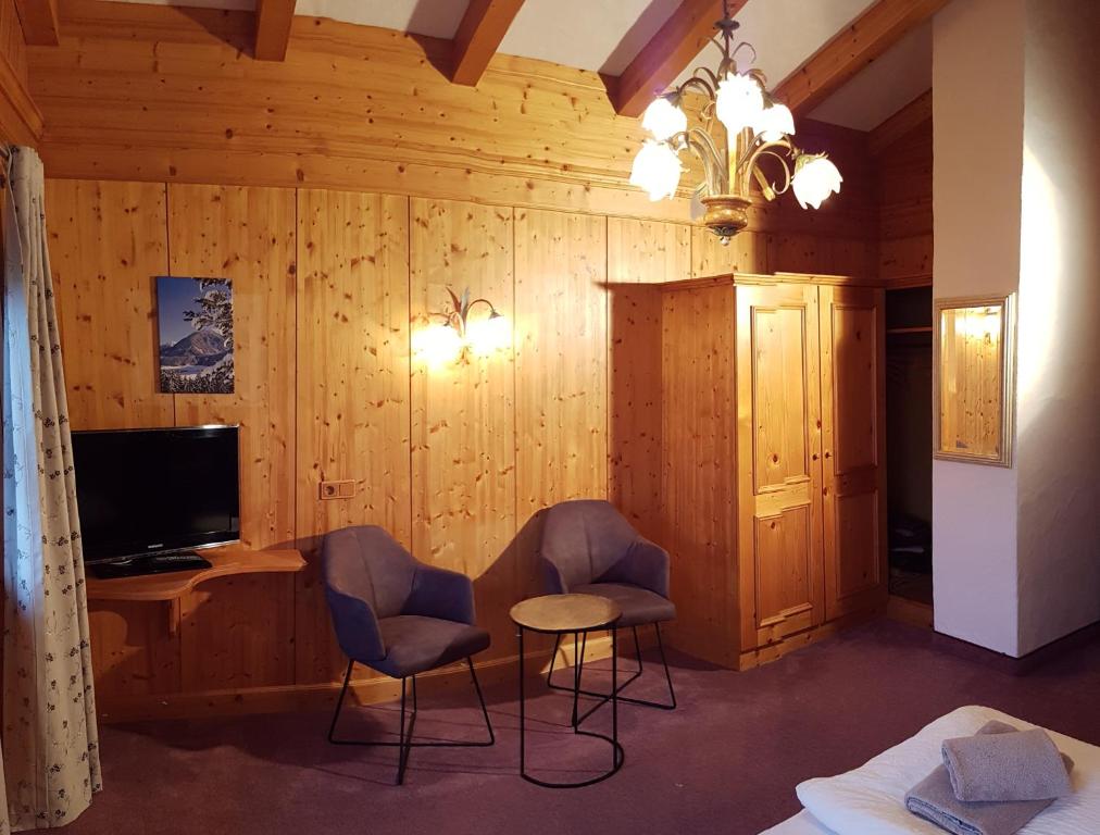 - un salon avec deux chaises et une télévision dans l'établissement Bauernhof Oberscheffau, à Neukirchen am Großvenediger