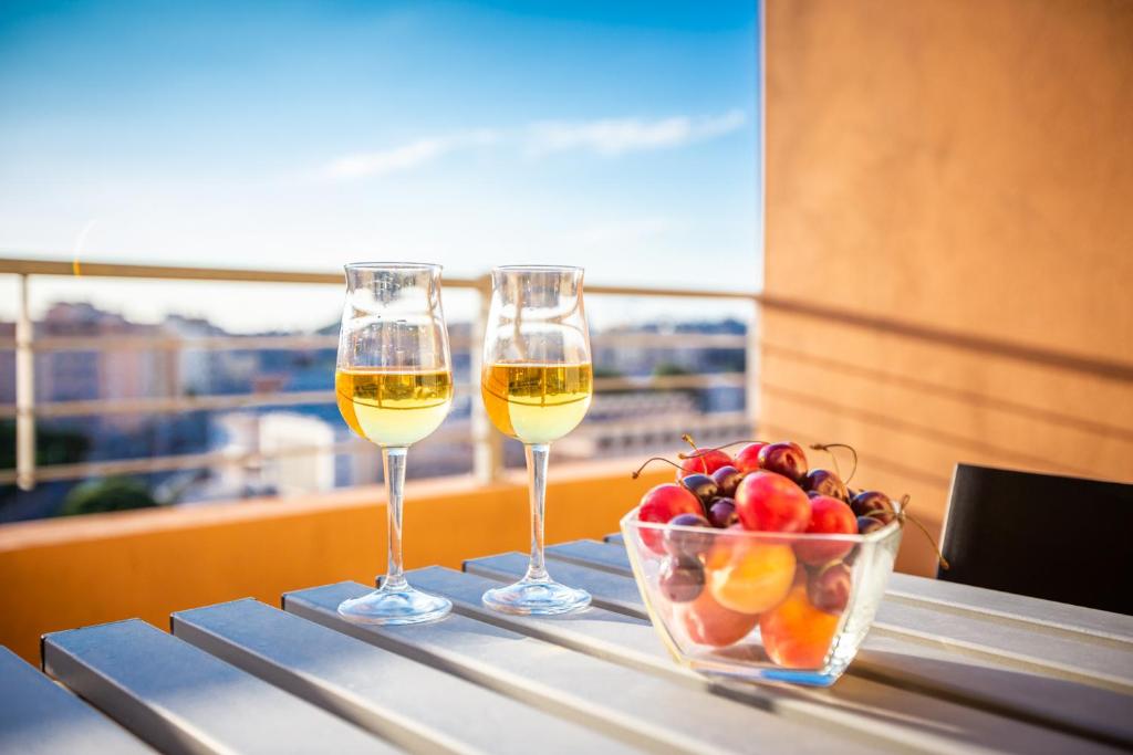 two glasses of wine and a bowl of fruit on a table at A View on Cagliari in Cagliari