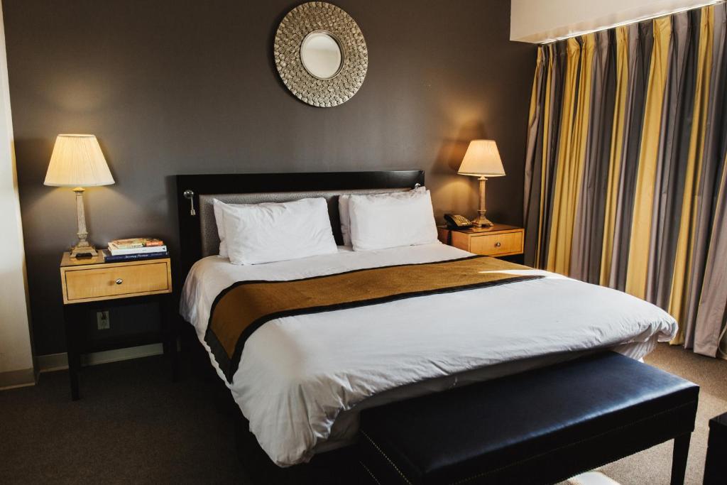 Bett in einem Hotelzimmer mit 2 Lampen und einem Spiegel in der Unterkunft Stamford Suites in Stamford