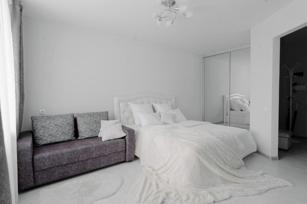 PaulMarie Apartments on Gor'kogo 41 في بابرويسك: غرفة نوم بيضاء مع سرير وأريكة