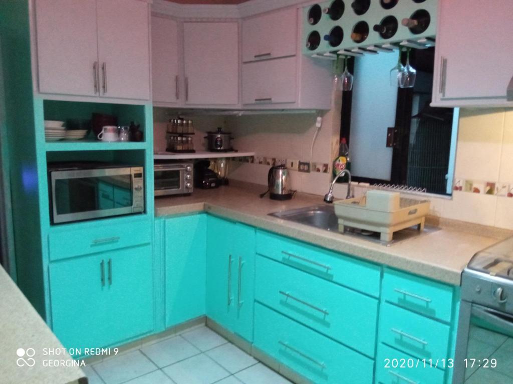 uma cozinha com armários azuis e um lavatório em Gina's house em Culiacán
