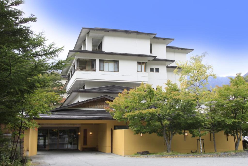 un bâtiment blanc avec des arbres devant lui dans l'établissement Yumori Kamaya, à Nikkō