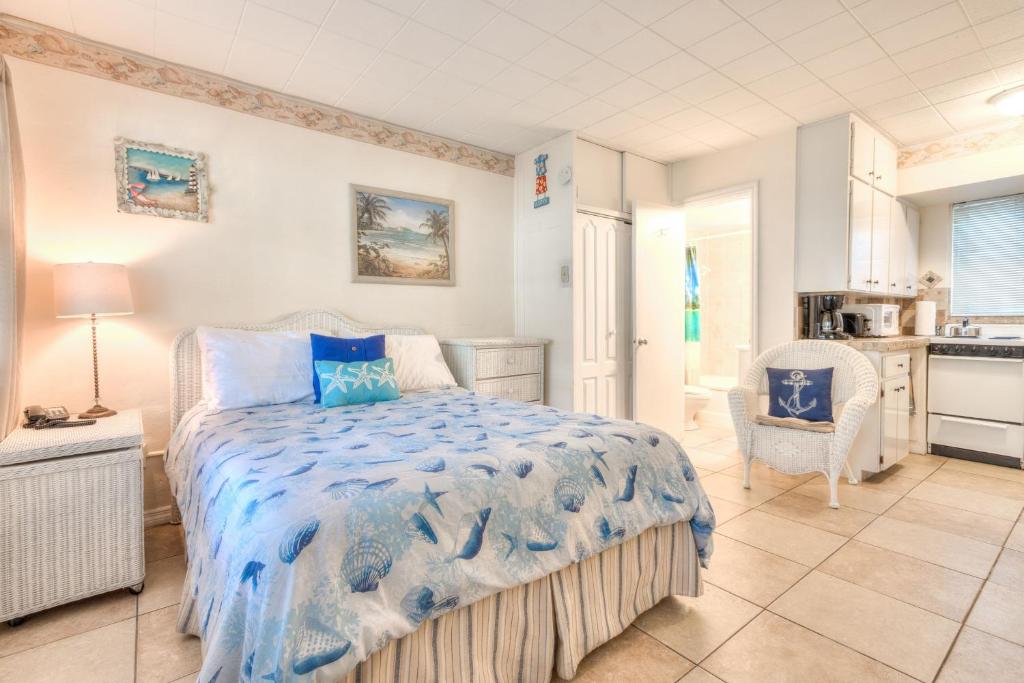 een slaapkamer met een bed en een stoel en een keuken bij Tropic Terrace #16 - Beachfront Rental apts in St Pete Beach