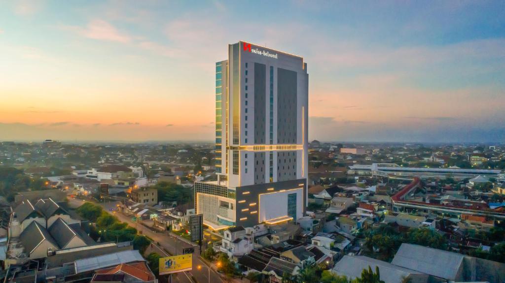 a tall building with a sign on it in a city at Swiss-Belhotel Solo in Solo