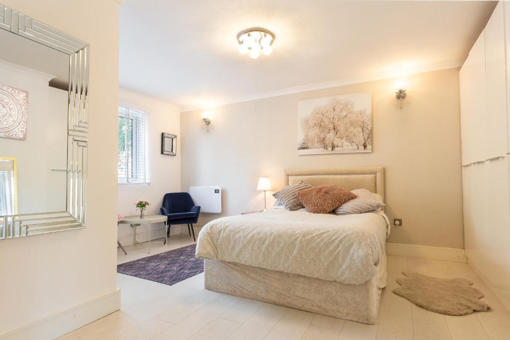 a bedroom with a bed and a chair and a mirror at Modern apartment close to central London (zone 2) in London