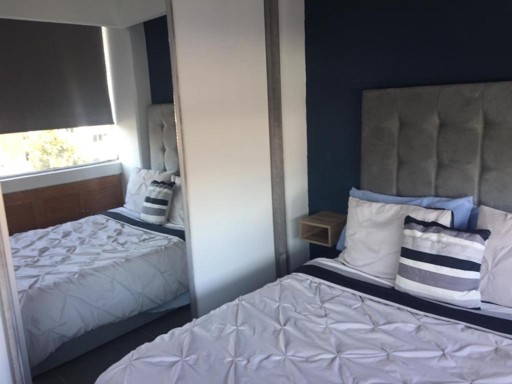 a mirror reflection of a bedroom with two beds at Blue Dreams Apartament Del Valle in Mexico City