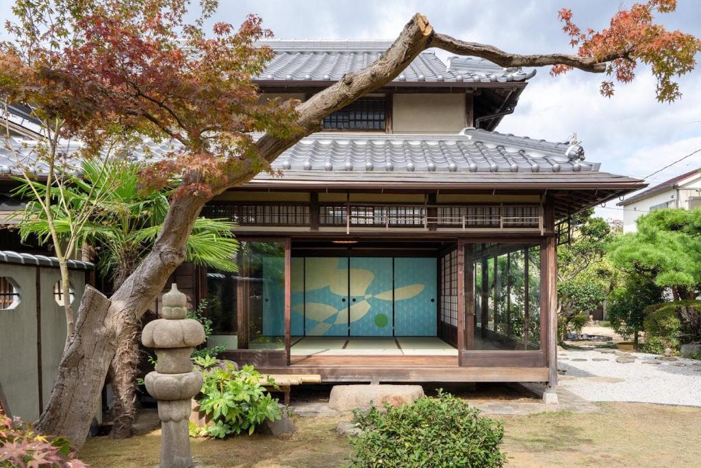 uma casa com uma porta de vidro e uma árvore em Osaka Sakainoma hotel Hama em Sakai