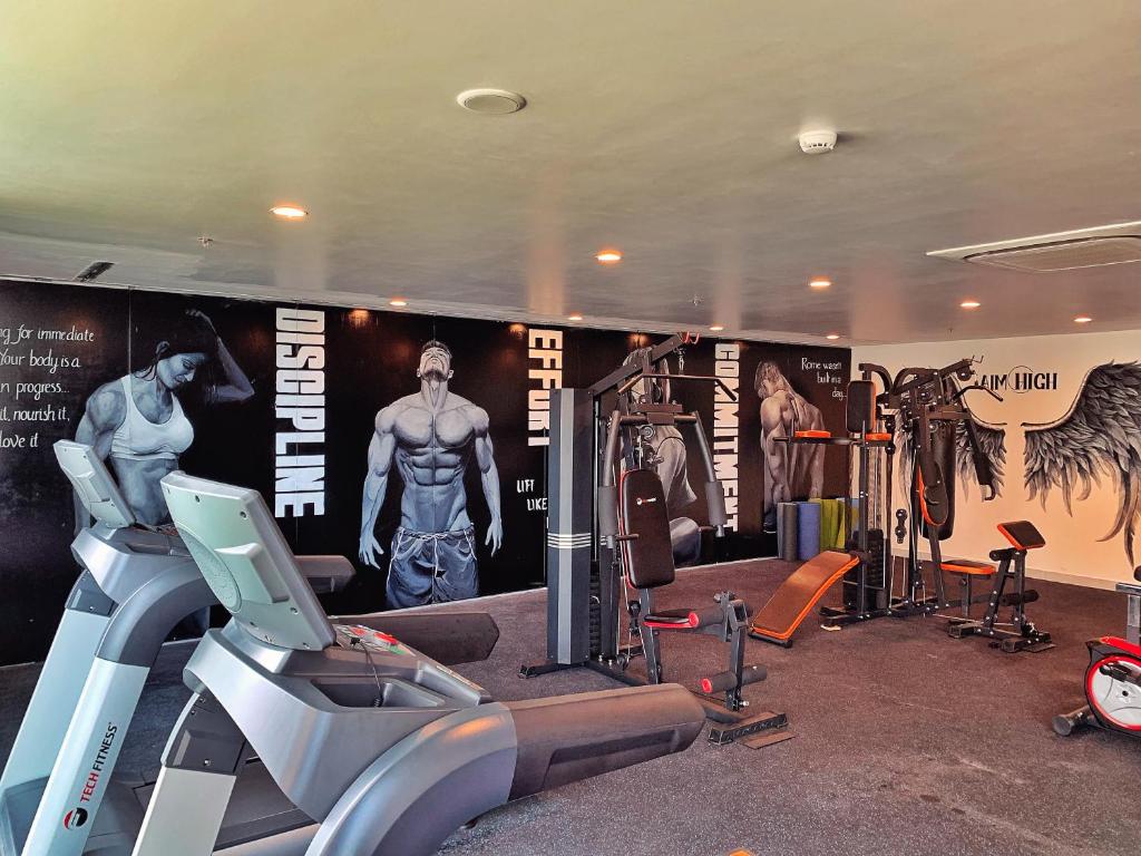 A compact gym with cardio equipment, weight machines and fitness posters.