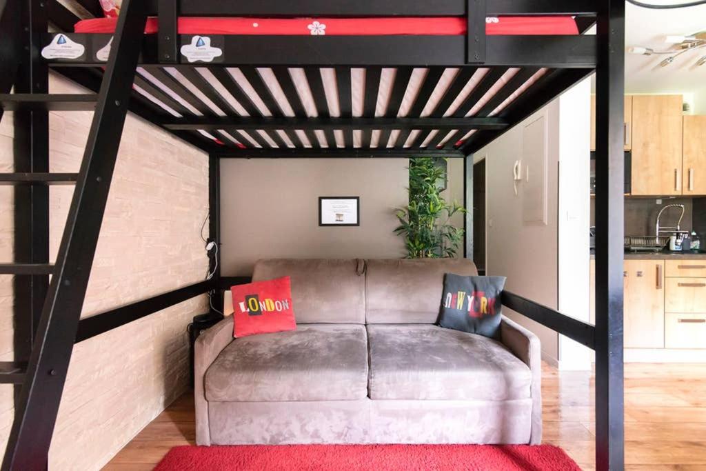 Una cama alta con un sofá en una habitación. en Nice Studio Near Mickey, Disneyland at 5mn, en Montévrain