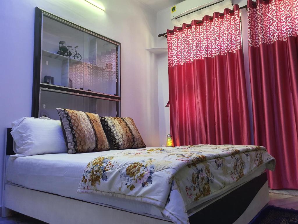 a bedroom with a bed and red curtains at Traverse Suite in Jaipur