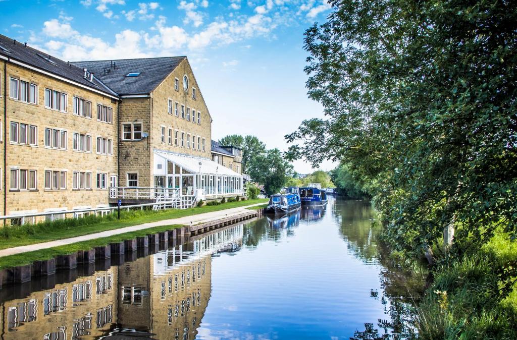 a canal in a city with buildings and boats at Hotel Rendezvous - Skipton - N Yorkshire in Skipton