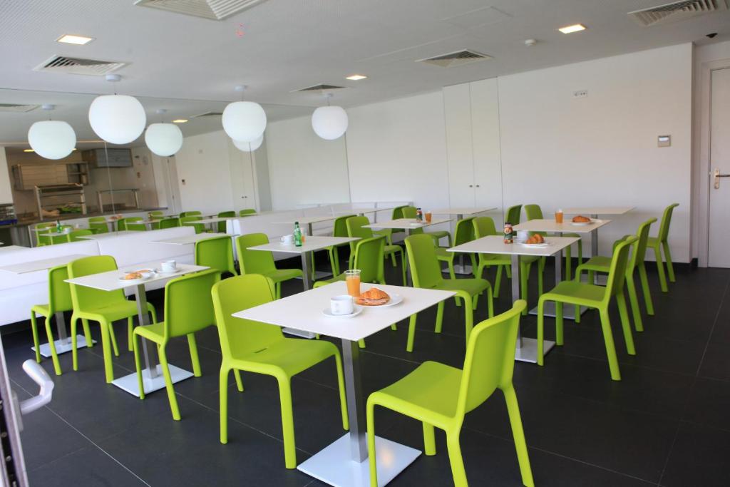 a dining room with tables and green chairs at Hotel 3K Faro Aeroporto in Faro