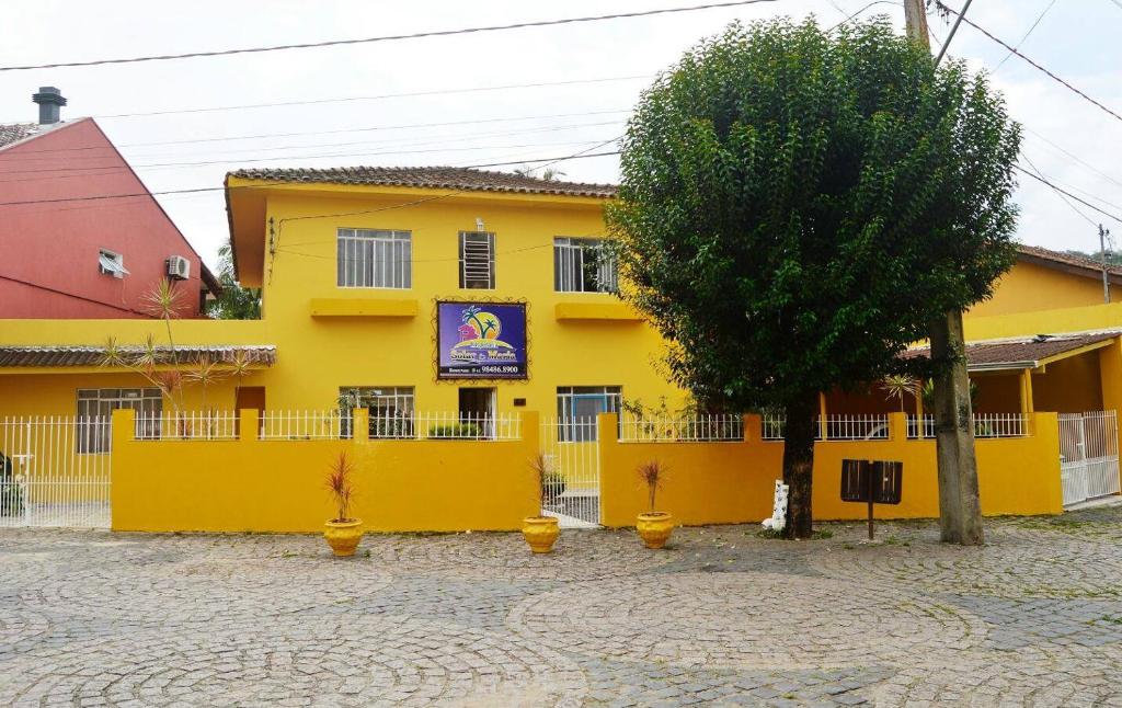 a yellow building with a tree in front of it at Hospedaria Solar De Morretes in Morretes