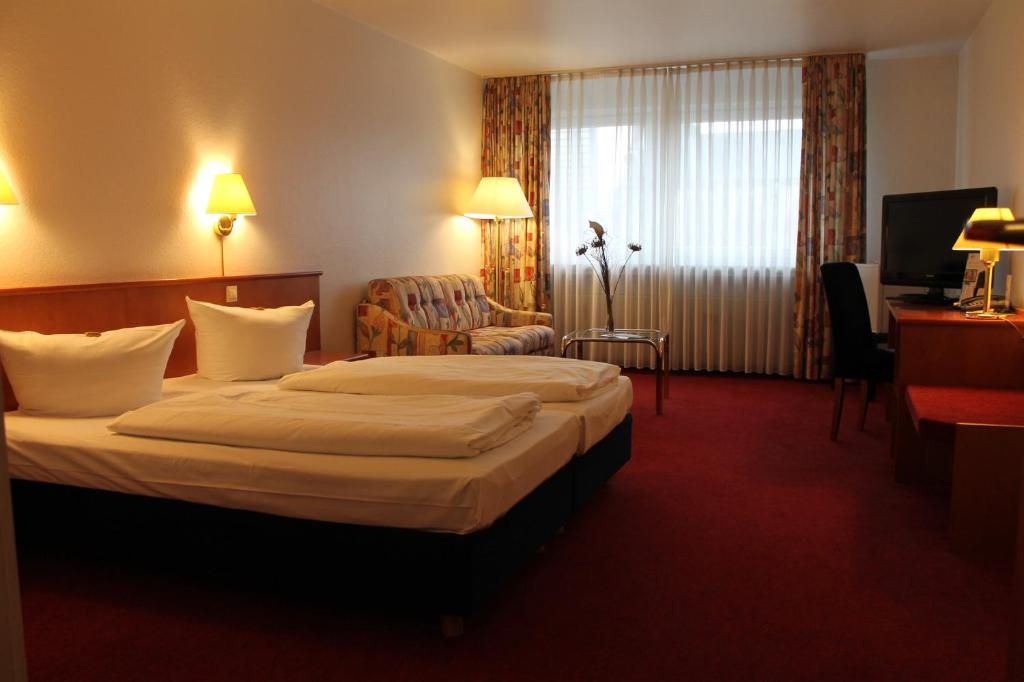 a hotel room with a large bed and a chair at City Hotel Essen in Essen
