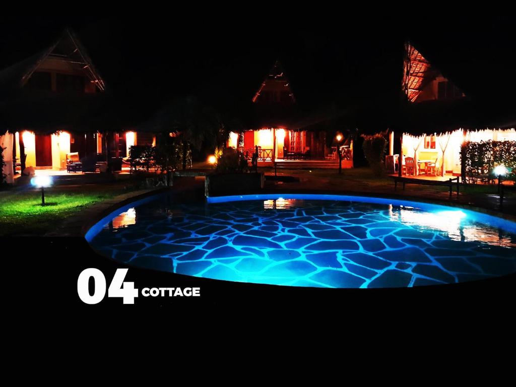 uma piscina iluminada à noite em 04 beach cottage malindi em Malindi