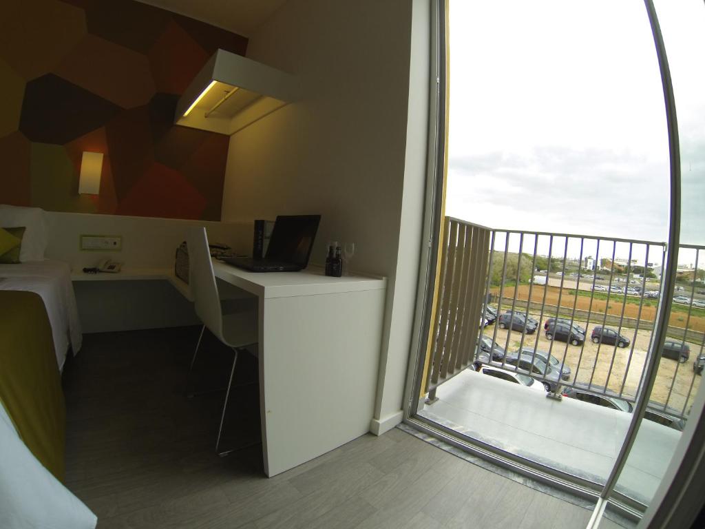 a room with a desk and a view of a balcony at Hotel 3K Faro Aeroporto in Faro