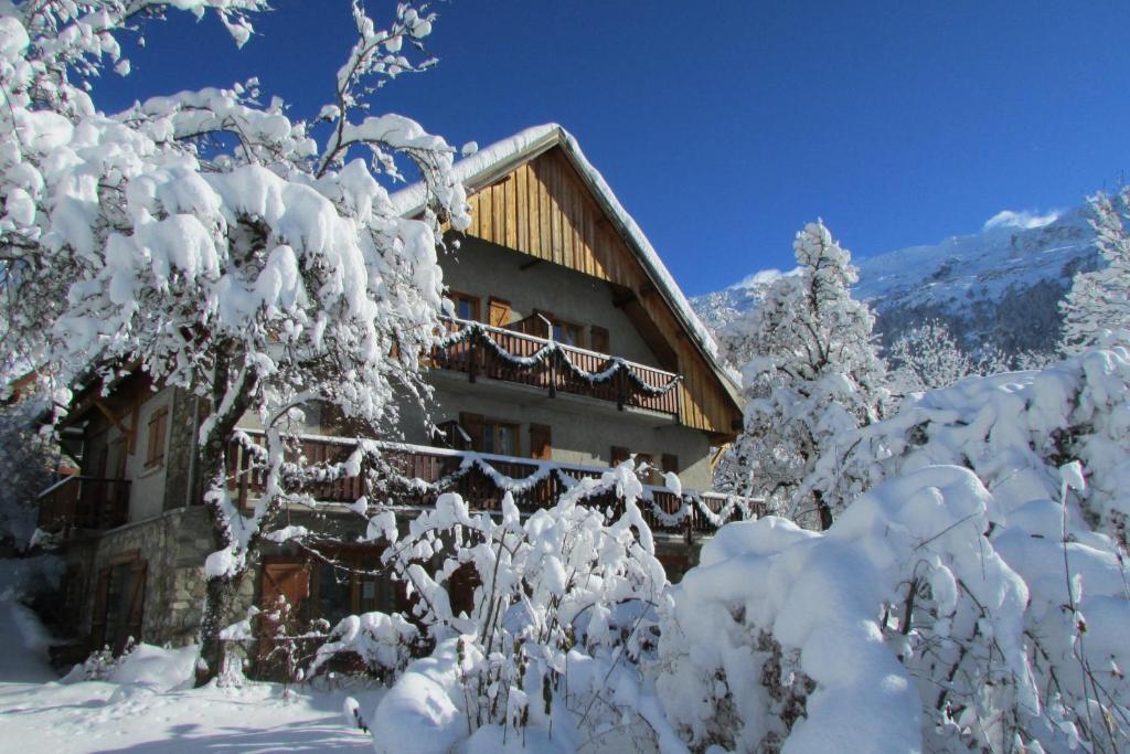 een gebouw bedekt met sneeuw en met sneeuw bedekte bomen bij Apartment Cerise in Vaujany