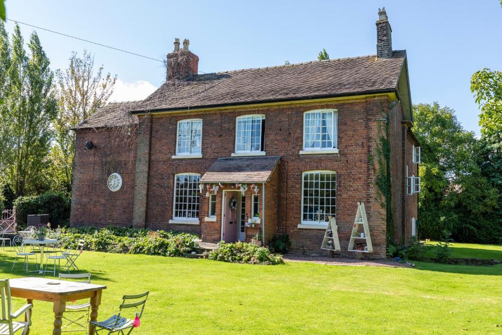 an old brick house with a table in the yard at Church Farm Guest House in Wellington