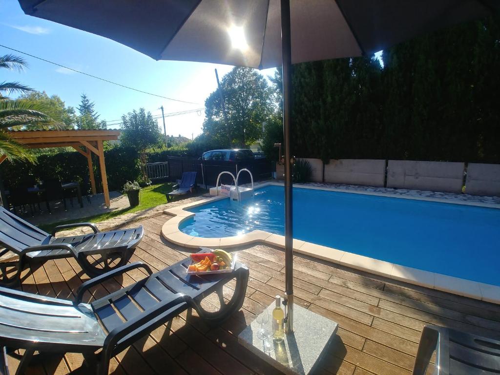 een zwembad met 2 stoelen en een parasol bij Lana Apartman in Medulin