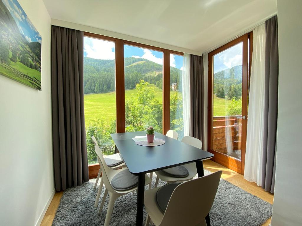 una sala da pranzo con tavolo, sedie e una grande finestra di Lisa apartman Bad Kleinkirchheim a Bad Kleinkirchheim