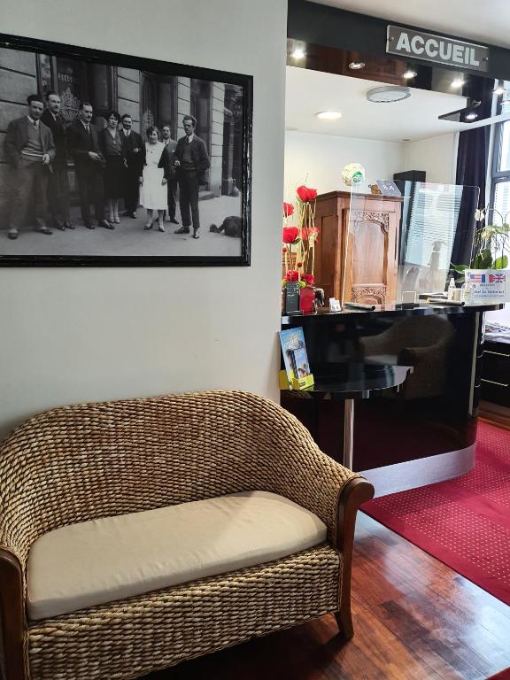 a wicker bench in a room with a picture on the wall at Hôtel Le National in Saint-Étienne