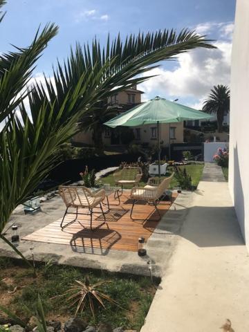a patio with two chairs and a green umbrella at Joaninha's Beach House in Glória
