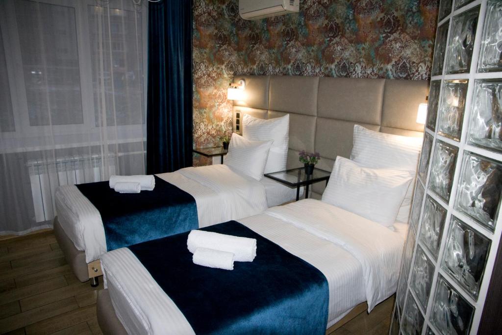 ベレズニキにあるMini-Otel' Barbarisのホテルルーム内のベッド2台(白と青のシーツ付)