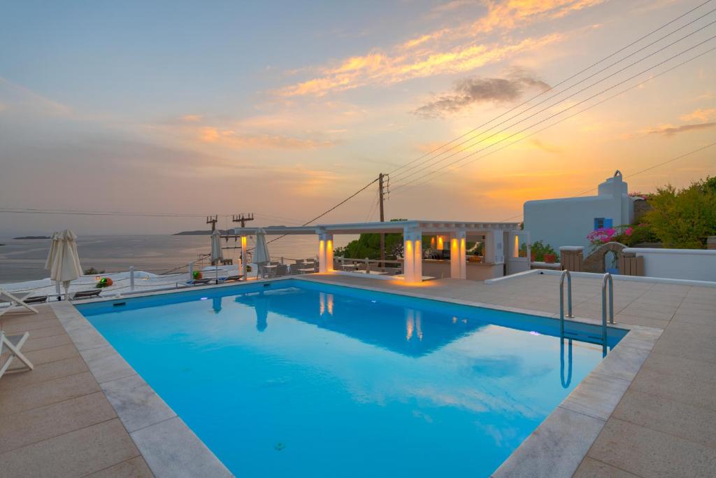 a swimming pool with a sunset in the background at Lithos by Spyros & Flora in Agios Ioannis Mykonos