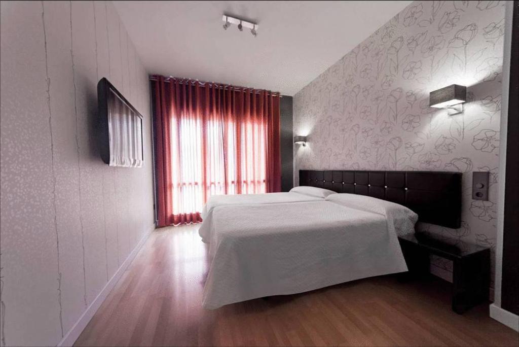 a bedroom with a white bed and a red window at Hospedium Hostal Un Punto Chic in Huesca