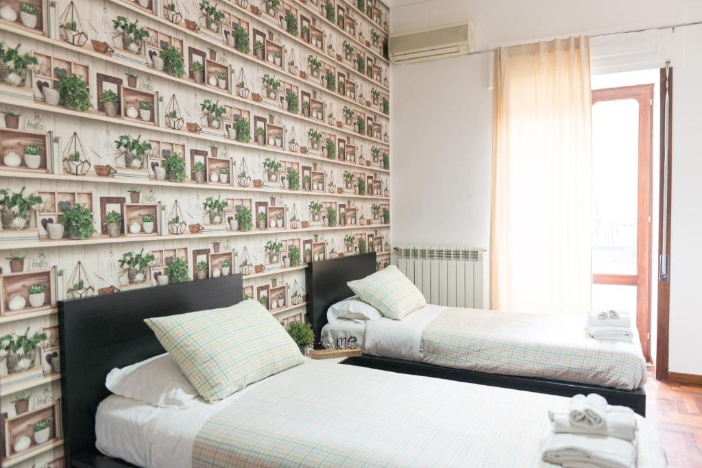 twee bedden in een kamer met een muur met planten bij Laetitia Guest House32 in Aversa
