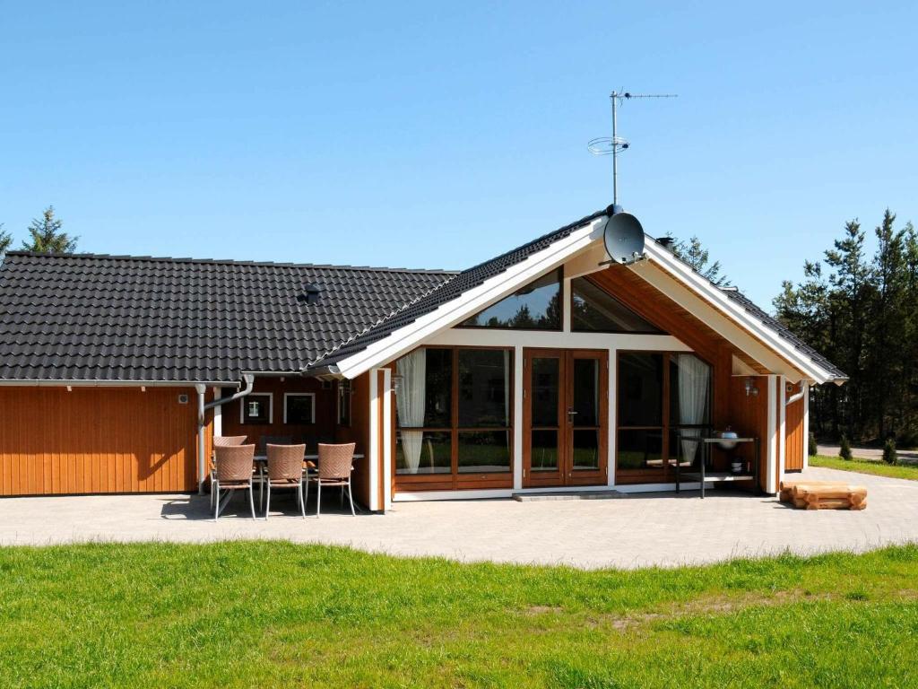 Sønder Nissumにある8 person holiday home in Ulfborgの大きなガラスのドアと椅子が備わる家