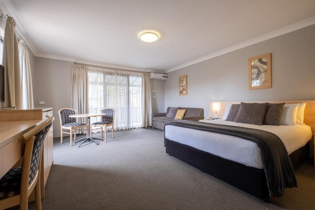 a bedroom with a bed and a desk and a couch at Maclin Lodge Motel in Campbelltown