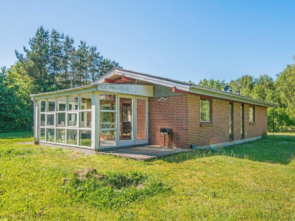 ein kleines Backsteinhaus mit einem Gewächshaus auf einem Feld in der Unterkunft 6 person holiday home in rsted in Udbyhøj