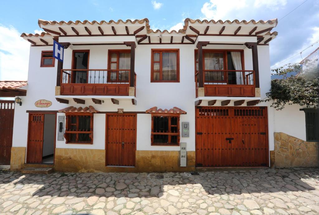 a white house with brown doors and windows at Hotel Aamayu in Villa de Leyva