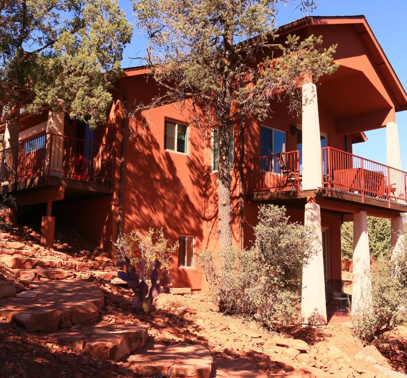 a large red house with balconies and trees at Cathedral Casita where indulgence meets peace and tranquility! in Sedona