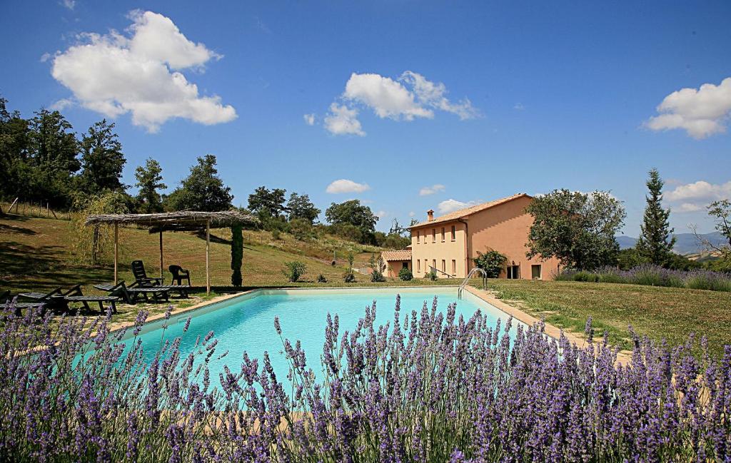 a swimming pool in front of a house with purple flowers at Villa Le Terme in San Casciano dei Bagni