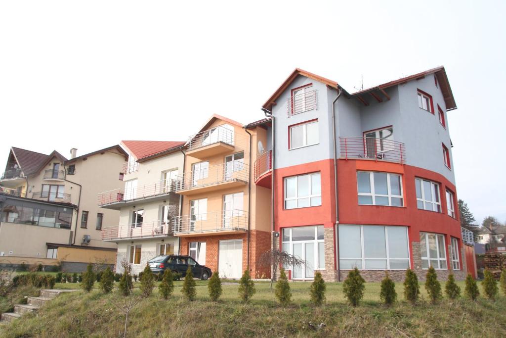 um edifício de apartamentos vermelho e branco com um carro estacionado em frente em Penzion Modul em Námestovo