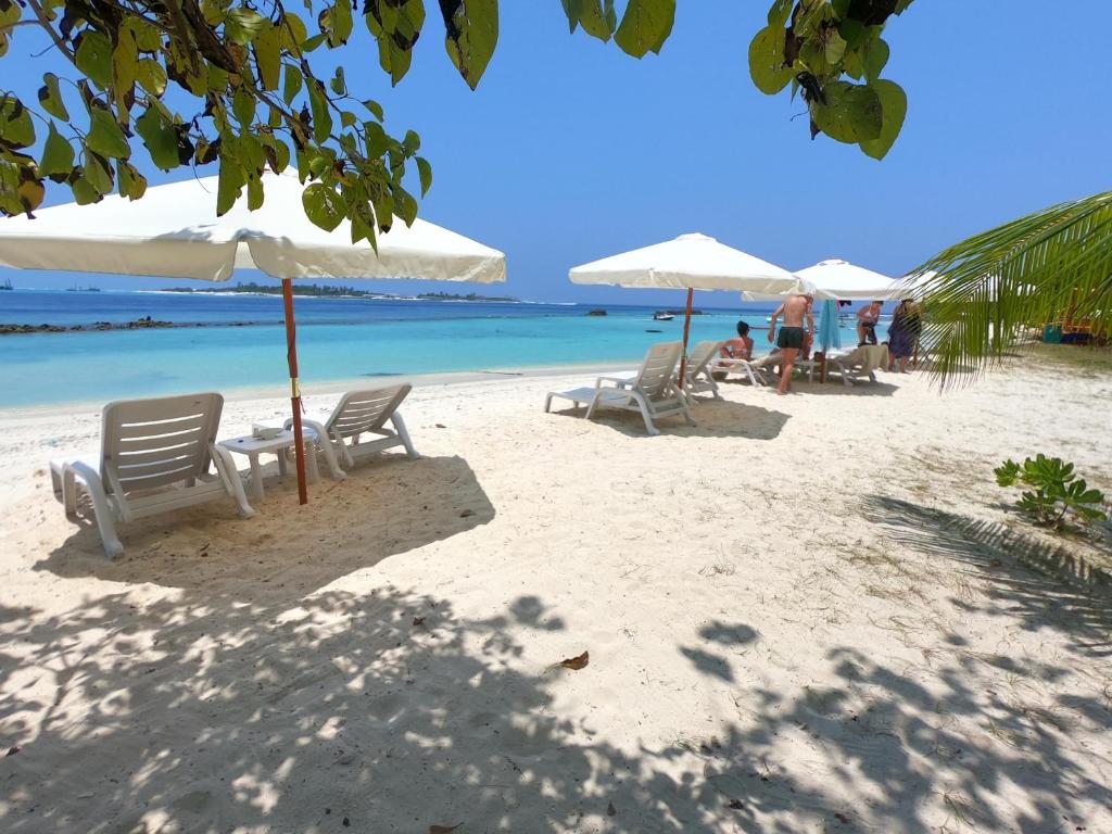 una playa con sillas y sombrillas y el océano en Kahanbu Ocean View, en Thulusdhoo