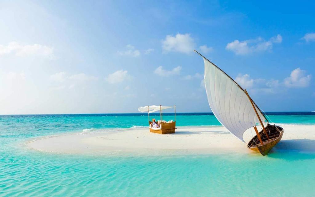 a boat with a white umbrella on a beach at Pearlshine Retreat Maldives in Gulhi