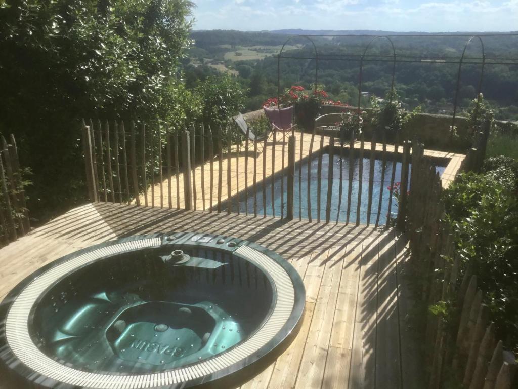 a hot tub on a wooden deck with a fence at 1 logis à Domme - Piscine & SPA in Domme