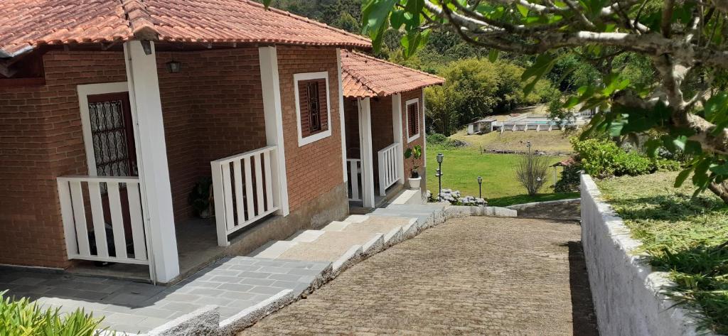 Una pequeña casa de ladrillo con una puerta blanca y escaleras. en Pousada Pedacinho do Ceu chale 2, en Cunha