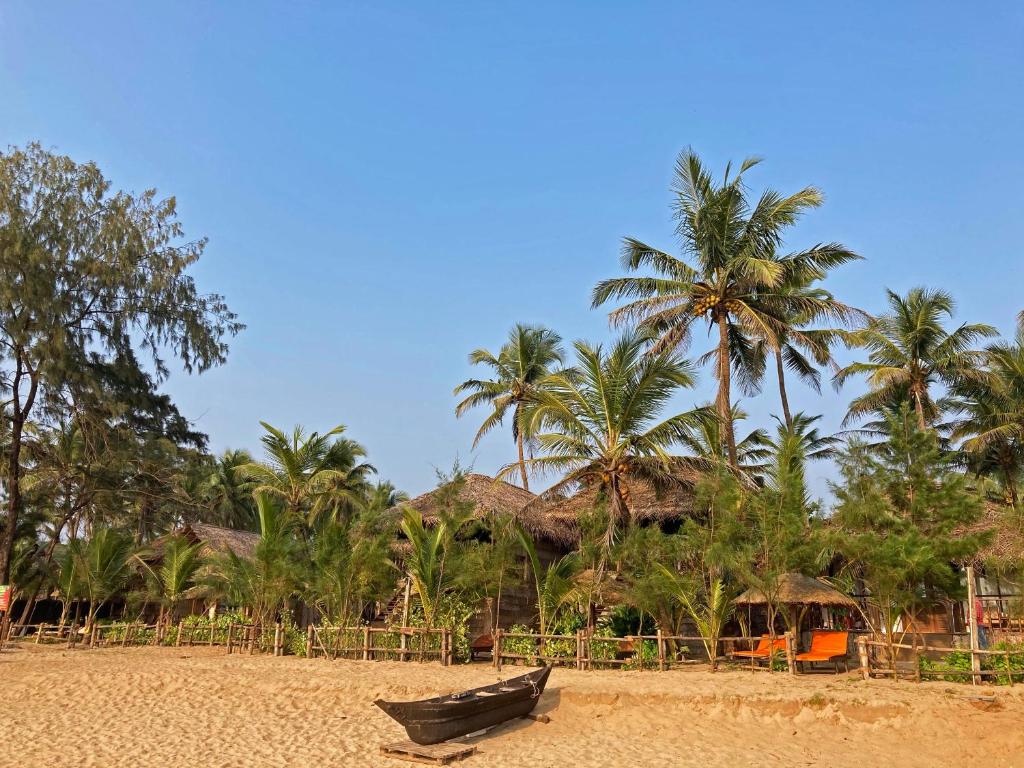 a boat on a sandy beach with palm trees at Agonda Villas in Agonda